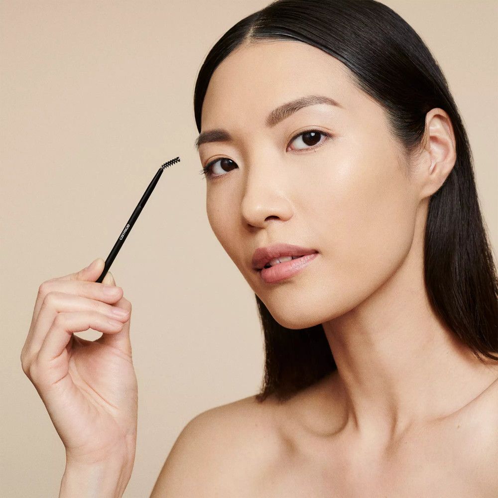 Vrouw met wenkbrauwstylingborstel. Zwarte borstel. Gezicht, blik richting camera.