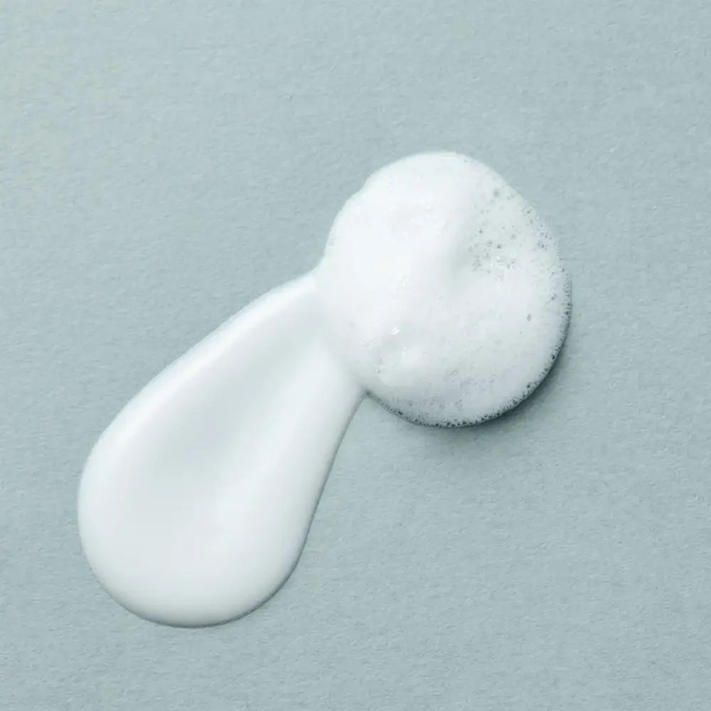 Wit schuim op grijze achtergrond. Schuim en crème. Textuur. Ovale vorm.