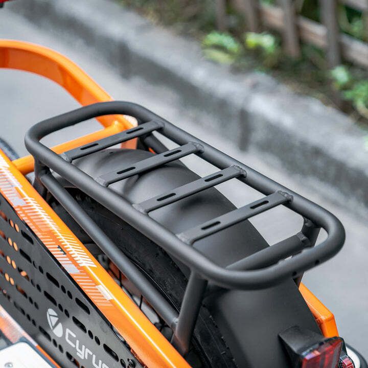 Zwarte bagagedrager op een oranje fiets. Rechthoekige vorm met dwarsbalken.