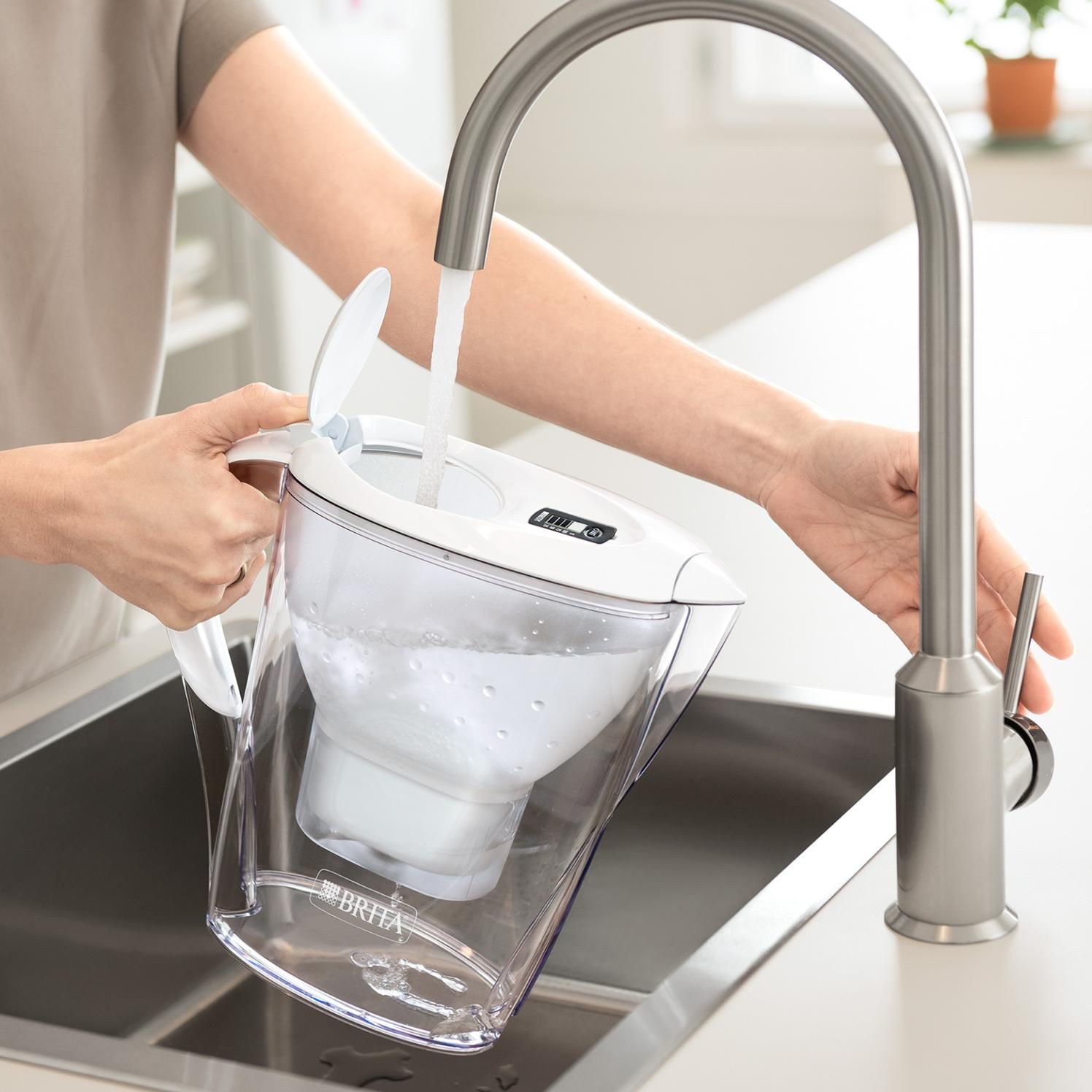 Carafe filtrante BRITA Marella XL remplie sous un robinet.