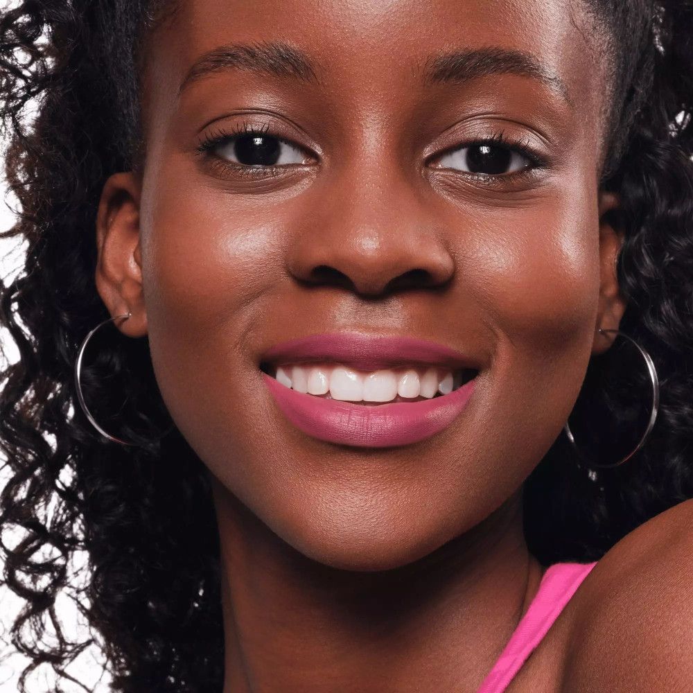 Portret van een vrouw met roze lippenstift. Ze glimlacht.