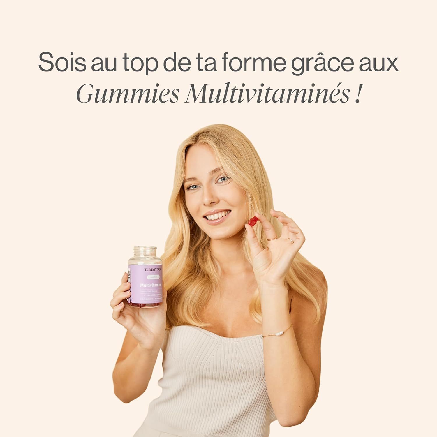 Une femme tient une bouteille de gommes Tummy Tox Multivitamines et une gomme individuelle.