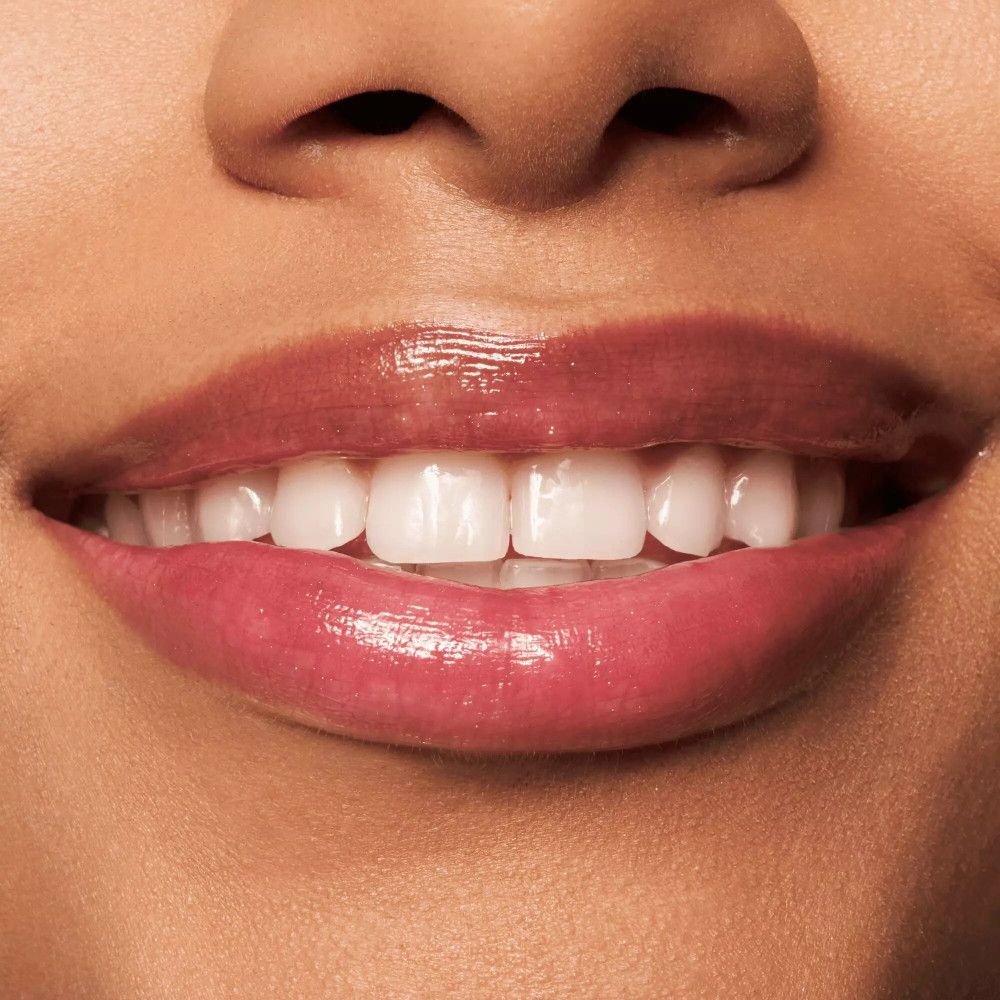 Gros plan sur les lèvres. Gloss brillant. Dents visibles.