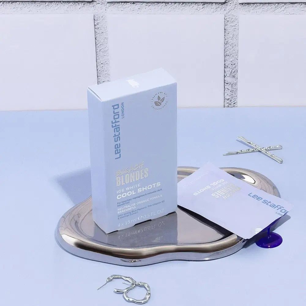 Lee Stafford Bleach Blondes Ice White Cool Shots sur un plateau avec deux sachets et des bijoux.