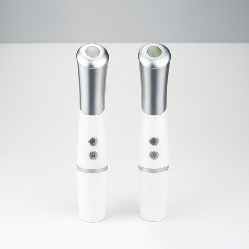 Twee witte oogmassagers met zilveren accenten en bedieningsknoppen.