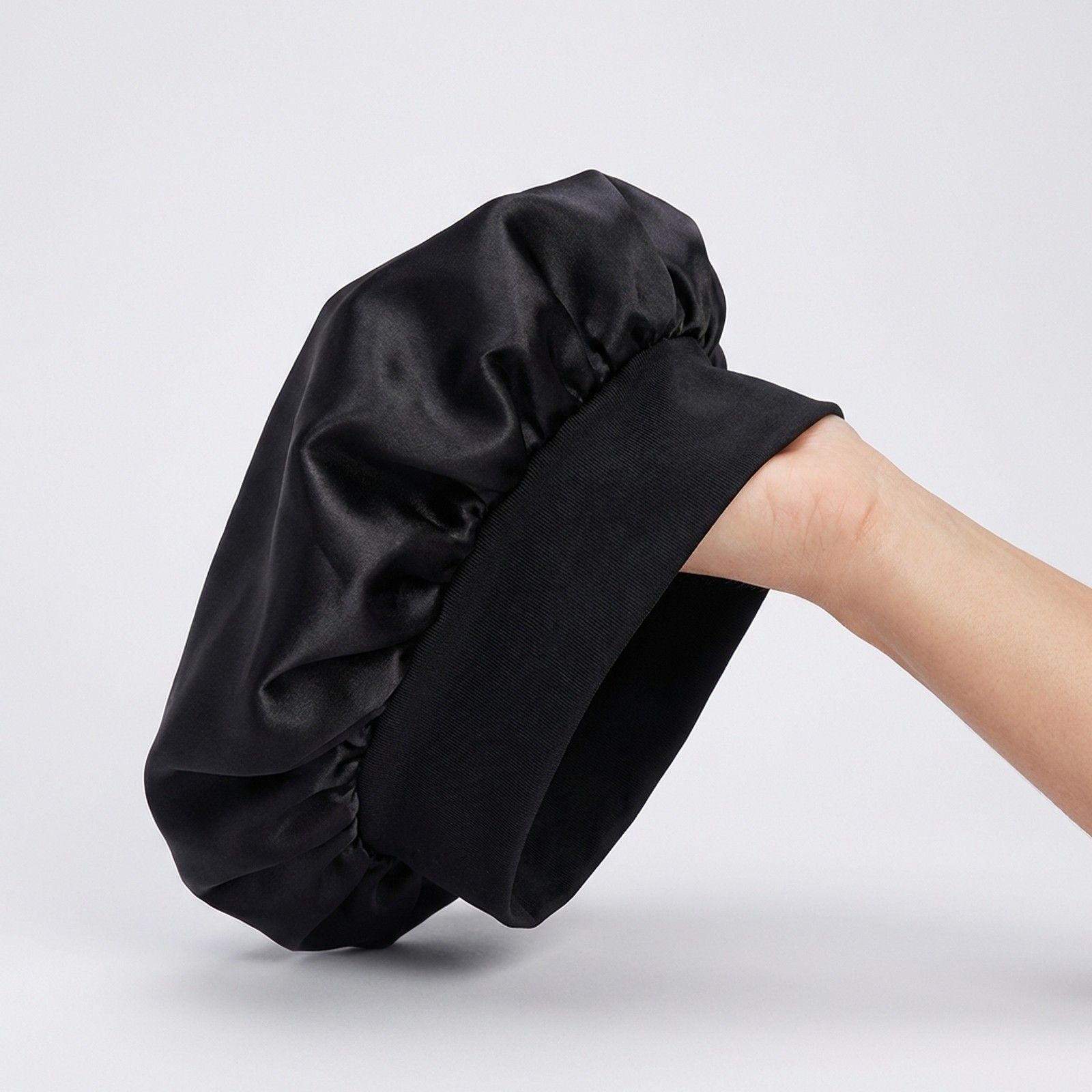 Bonnet de nuit noir en satin avec une large bande élastique.