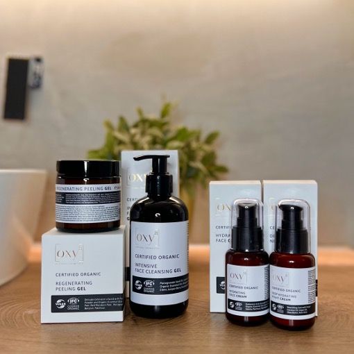 Set van peeling, wasgel, dag- en nachtcrème. Producten in bruine flessen en potten. Verpakking met productnamen.