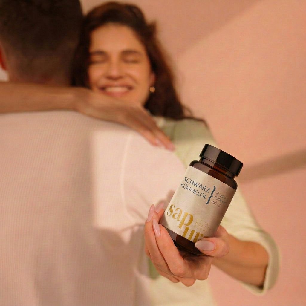 Vrouw omhelst man en houdt een flesje sapura zwarte komijnzaadolie capsules vast.