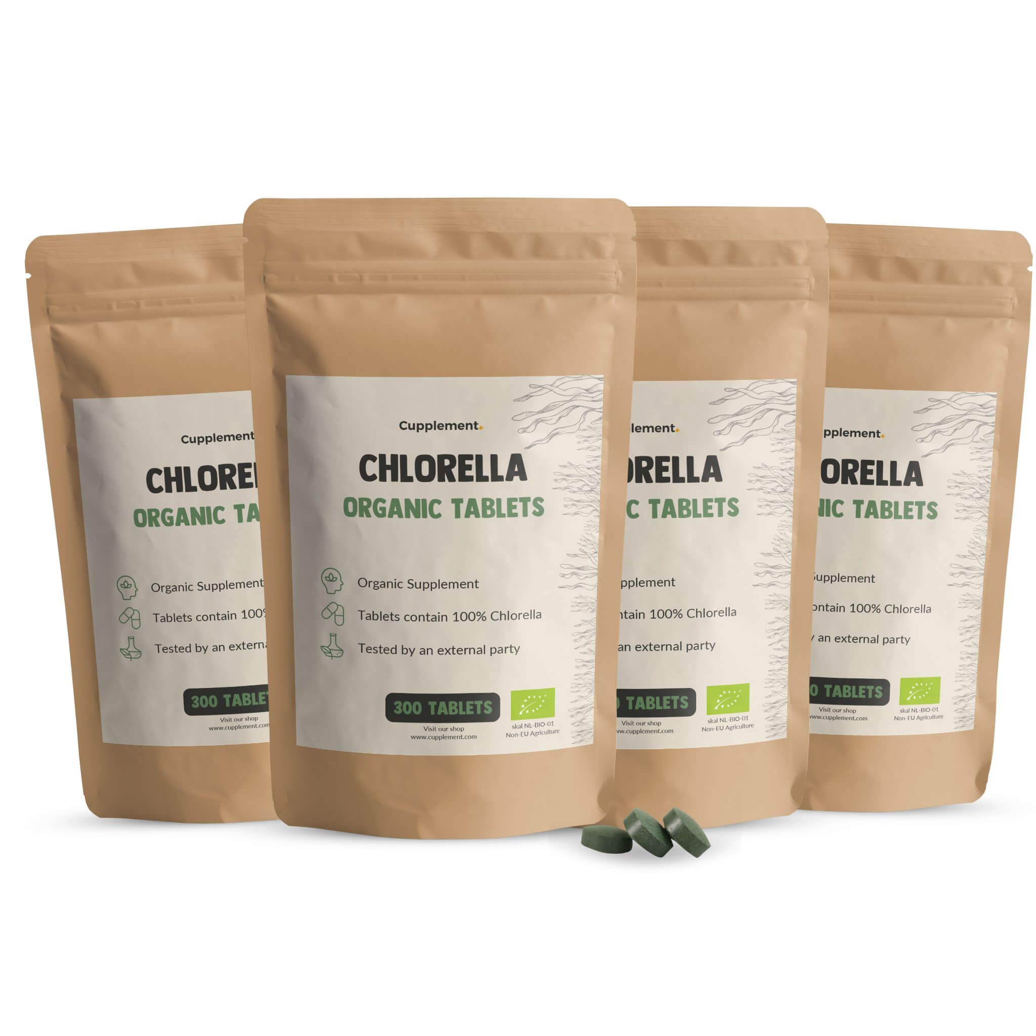 Vier zakken Cupplement Chlorella tabletten. Bruine verpakking met wit etiket. 300 tabletten. Groene tabletten ernaast.