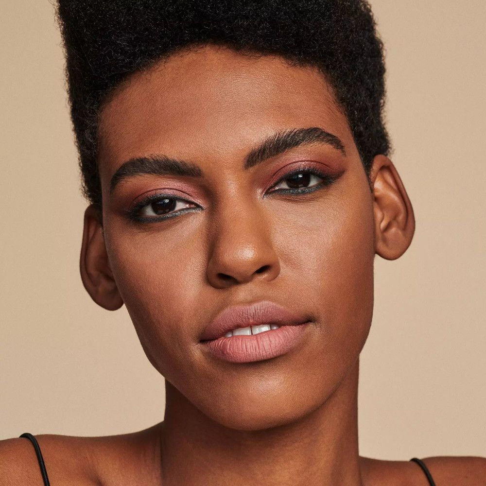 Portrait d'une femme avec eye-liner et fard à paupières. Elle a les cheveux courts et le teint clair.