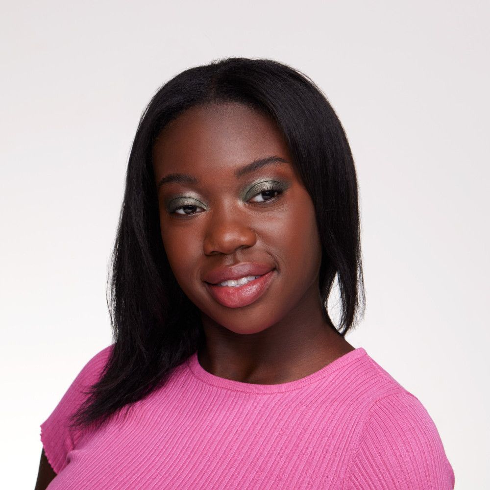 Portret van een vrouw met groene oogschaduw. Ze draagt een roze top.