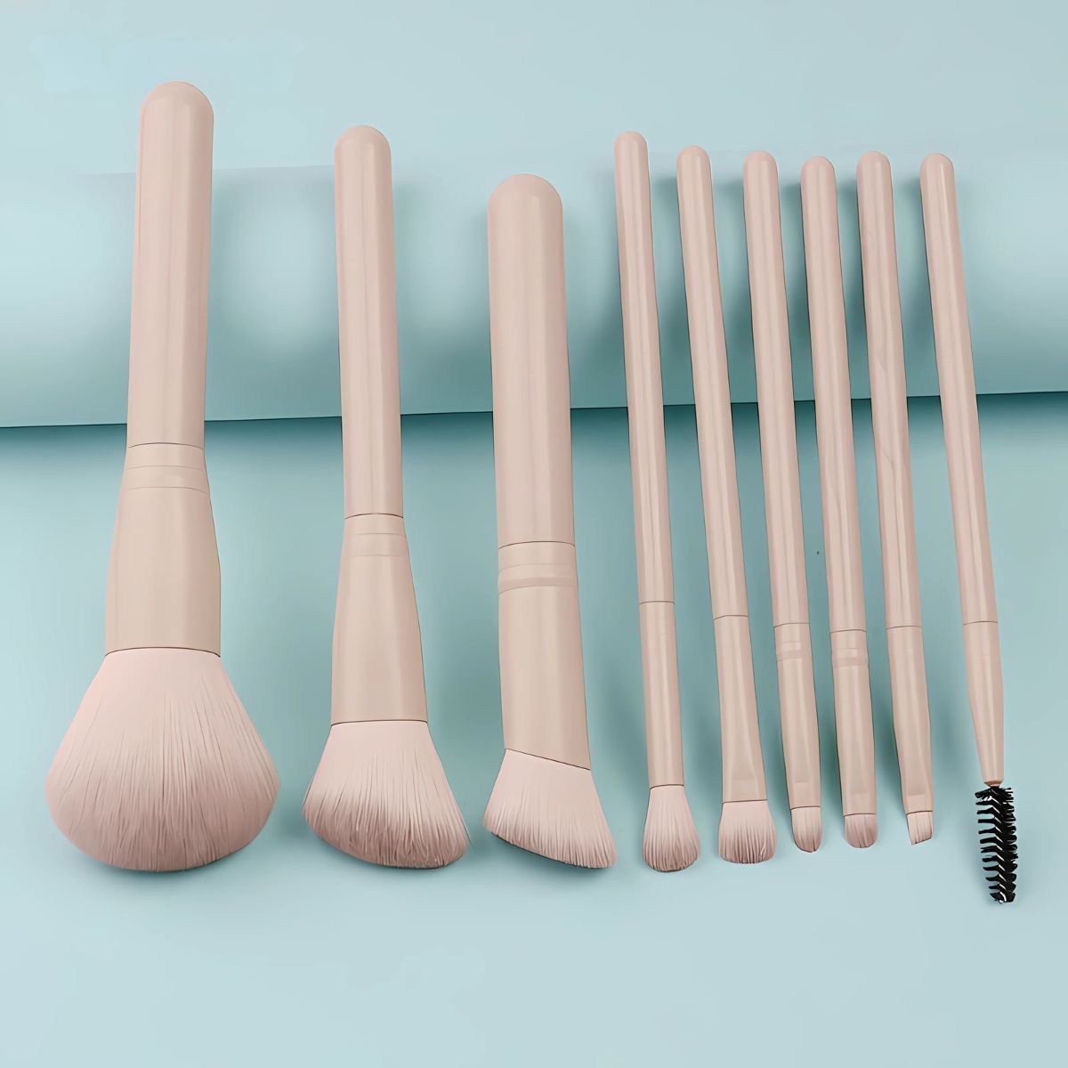 Un ensemble de huit pinceaux de maquillage beige clair avec des têtes variées et une brosse en spirale.
