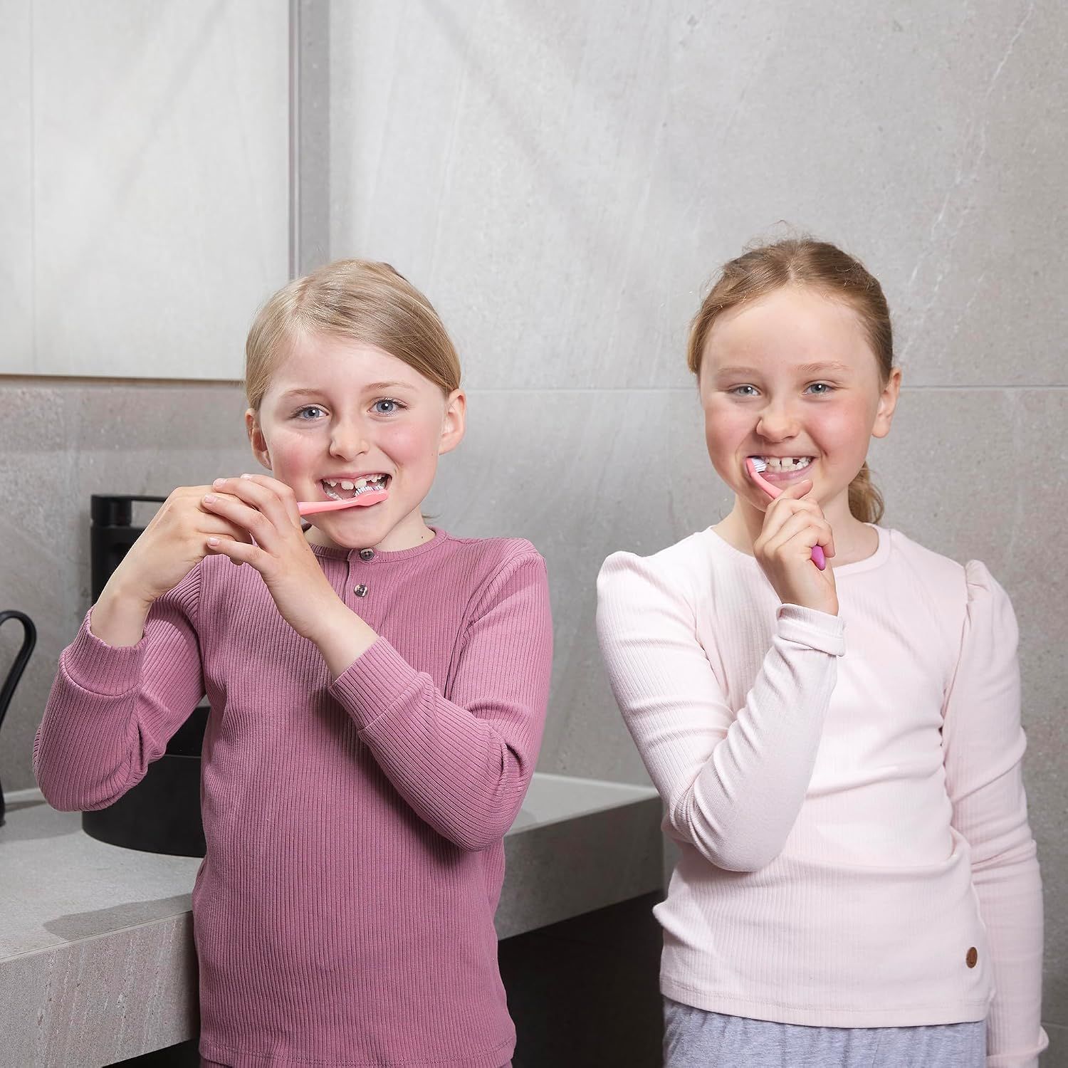 Deux filles se brossent les dents dans la salle de bain.