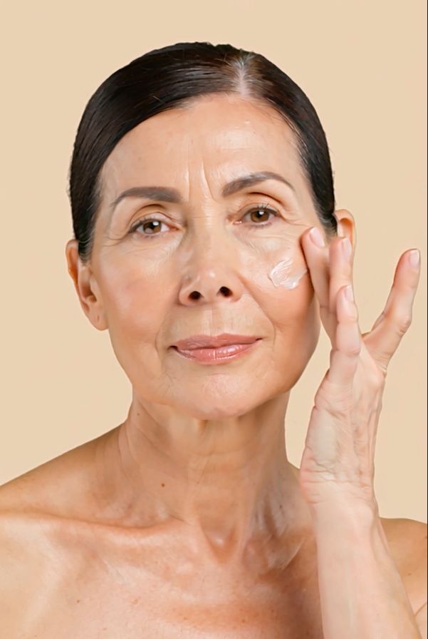 Oudere vrouw brengt crème aan op haar gezicht. Crème op de vinger.