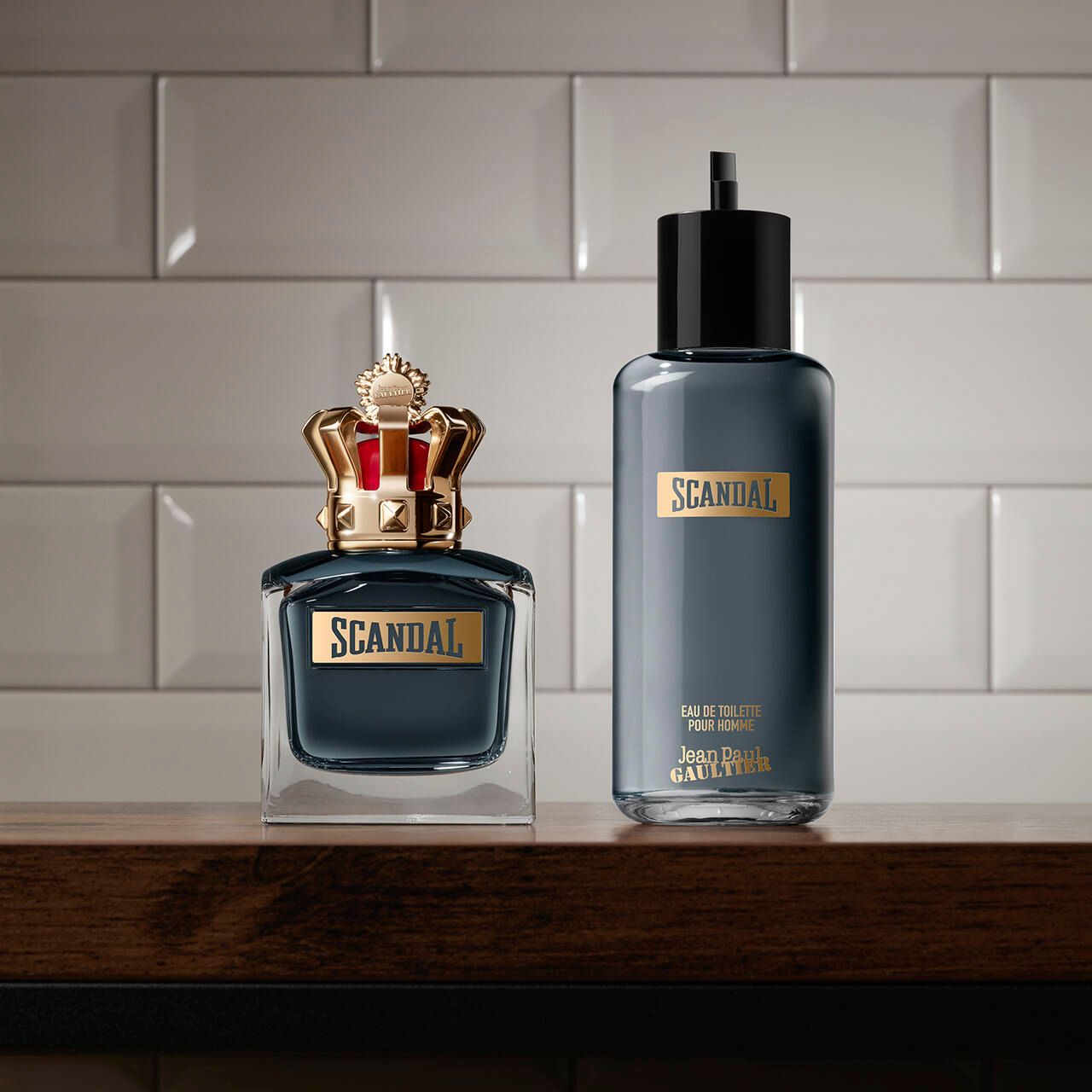 Flacon de parfum et bouteille avec couronne dorée. Inscription "SCANDAL" et "Jean Paul Gaultier".