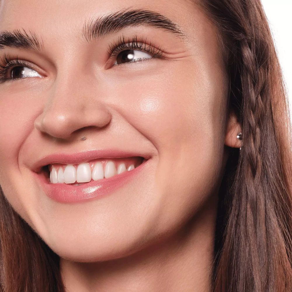 Portret van een vrouw met Essence Hydra Kiss Lip Oil op haar lippen. Ze glimlacht.