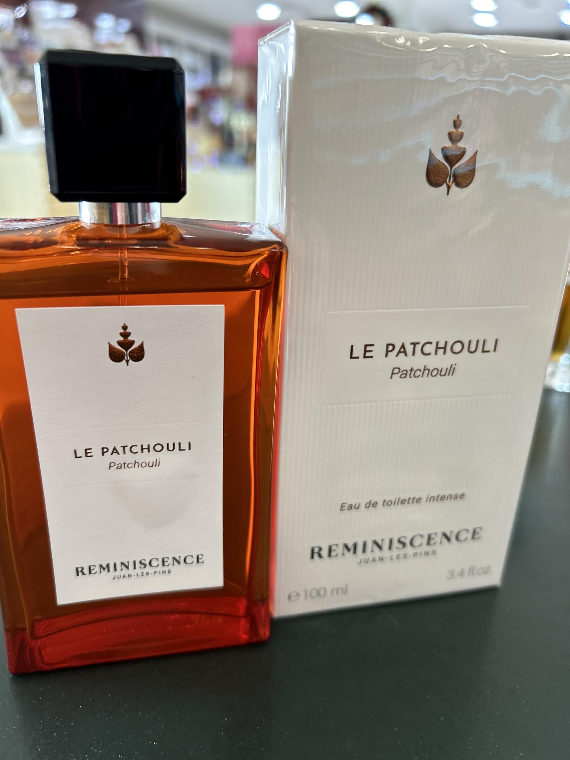 Flacon et emballage. Flacon rectangulaire marron avec bouchon noir. Emballage blanc avec logo et texte.