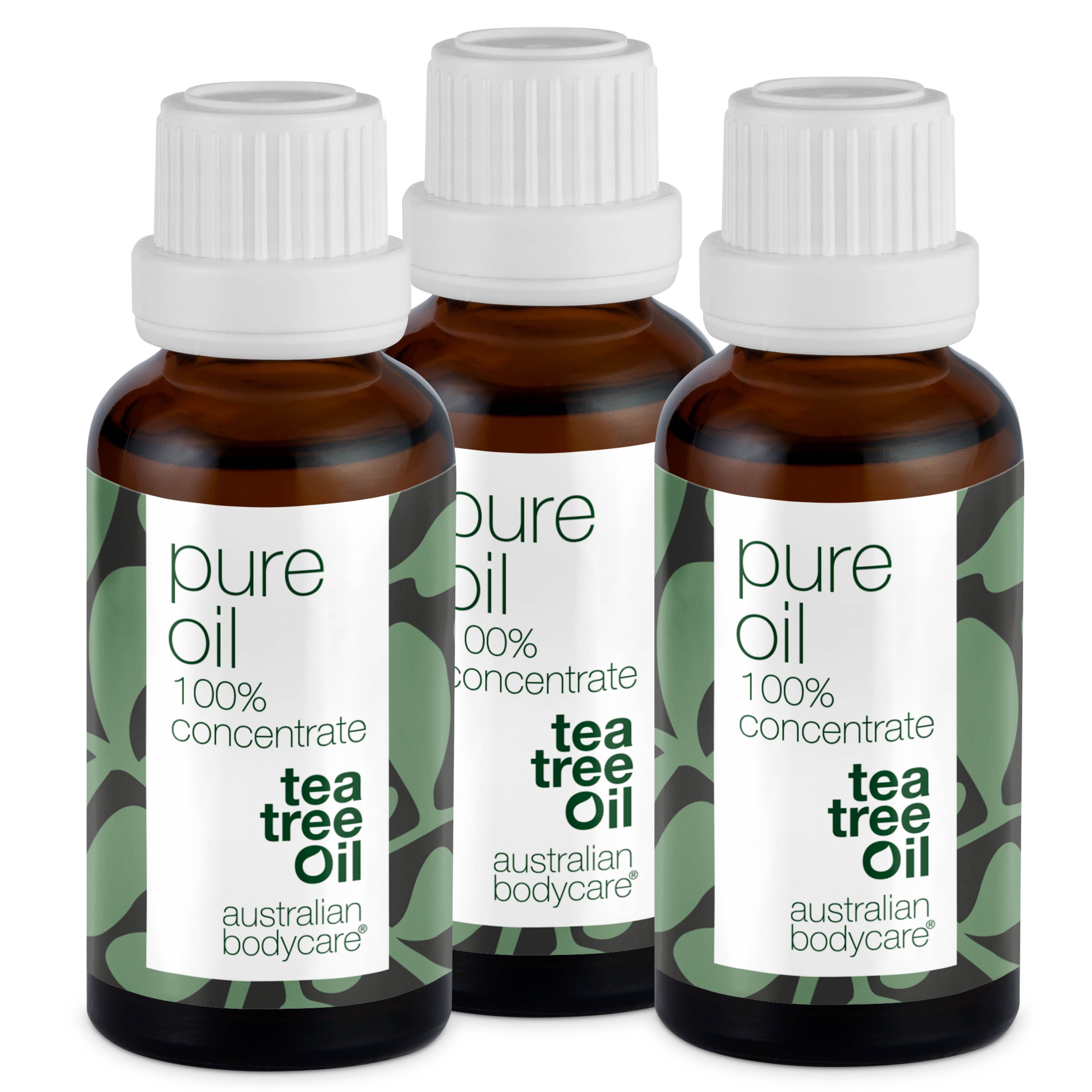 Drie flessen tea tree olie. Bruine glazen flessen met witte dop. Opschrift: Pure Oil, 100% Concentrate, Tea Tree Oil.