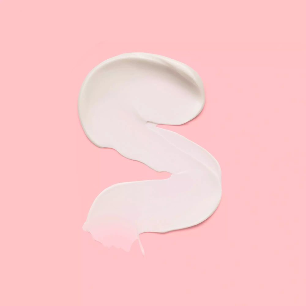 Trait de primer blanc sur fond rose. Forme: en forme de S. Texture: crémeuse.