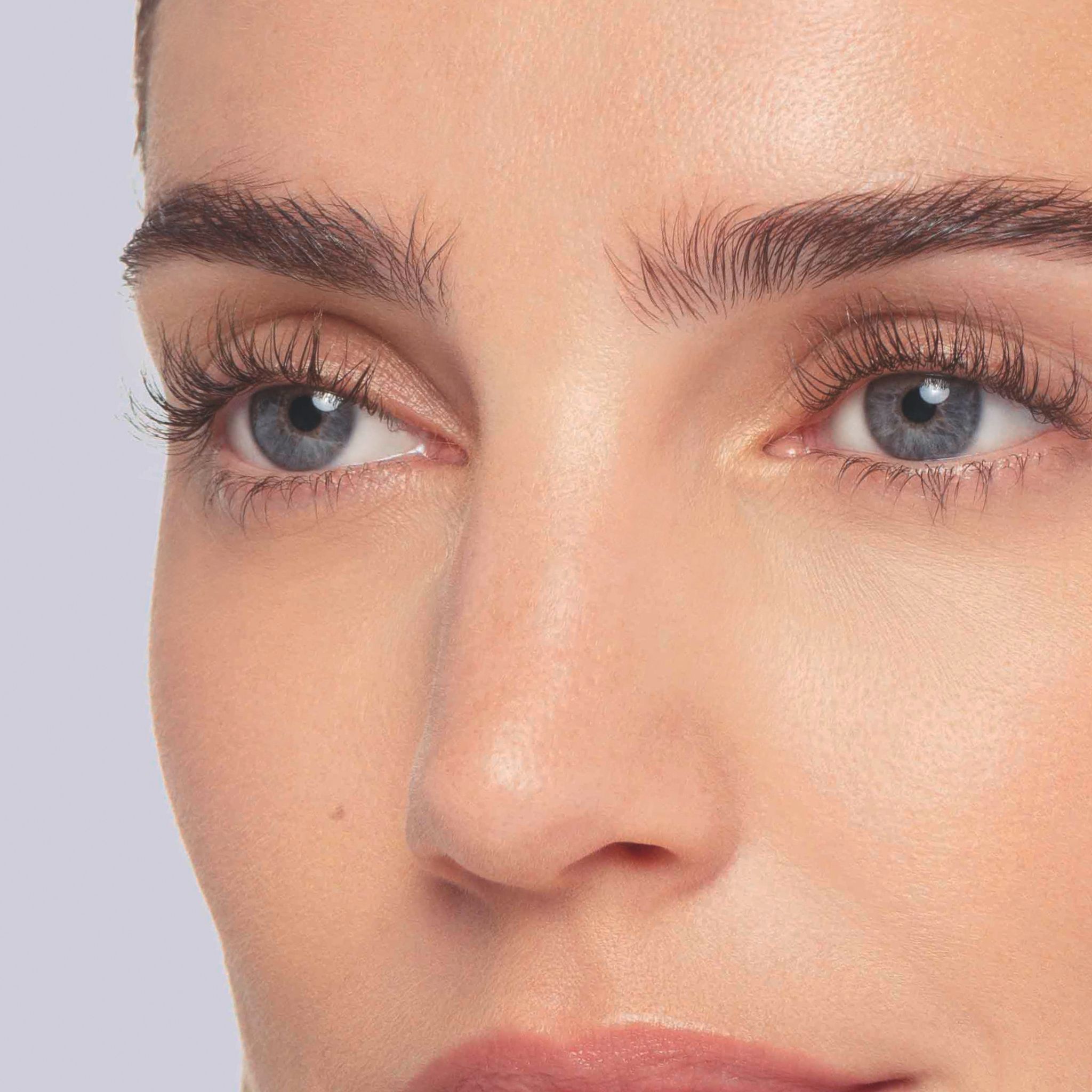 Gros plan des yeux bleus d'une femme aux cils parfaitement recourbés.