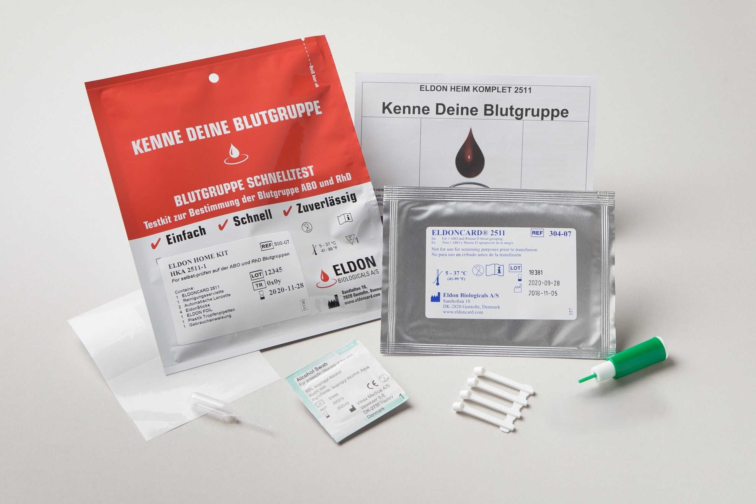 Bloedgroep testkit. Rode en zilveren verpakkingen, testkaarten, lancet, instructies. Tekst: Eldon, bloedgroep, sneltest.