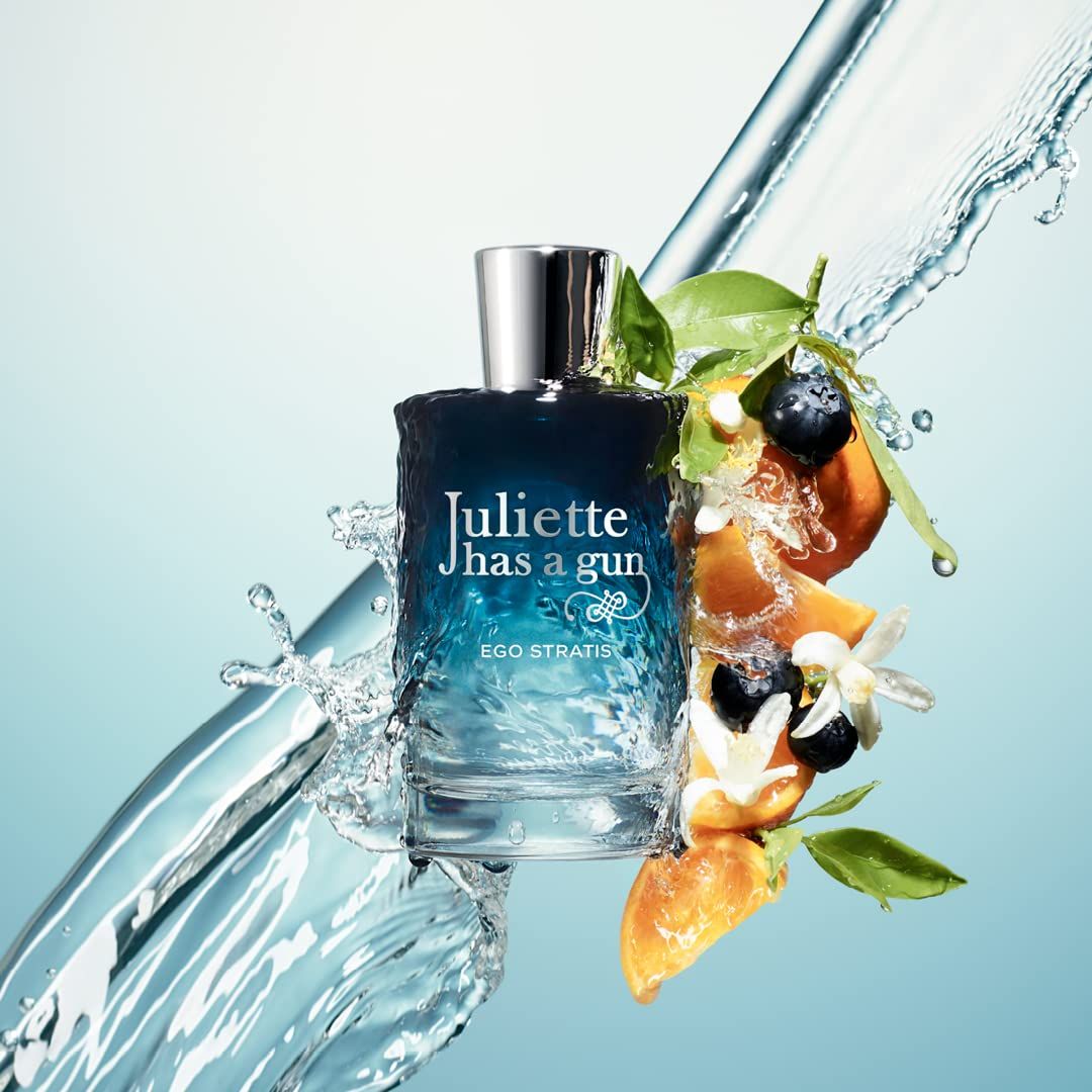 Glazen fles met zilveren dop, omringd door water, fruit en bloemen. Opschrift: Juliette has a gun EGO STRATIS.