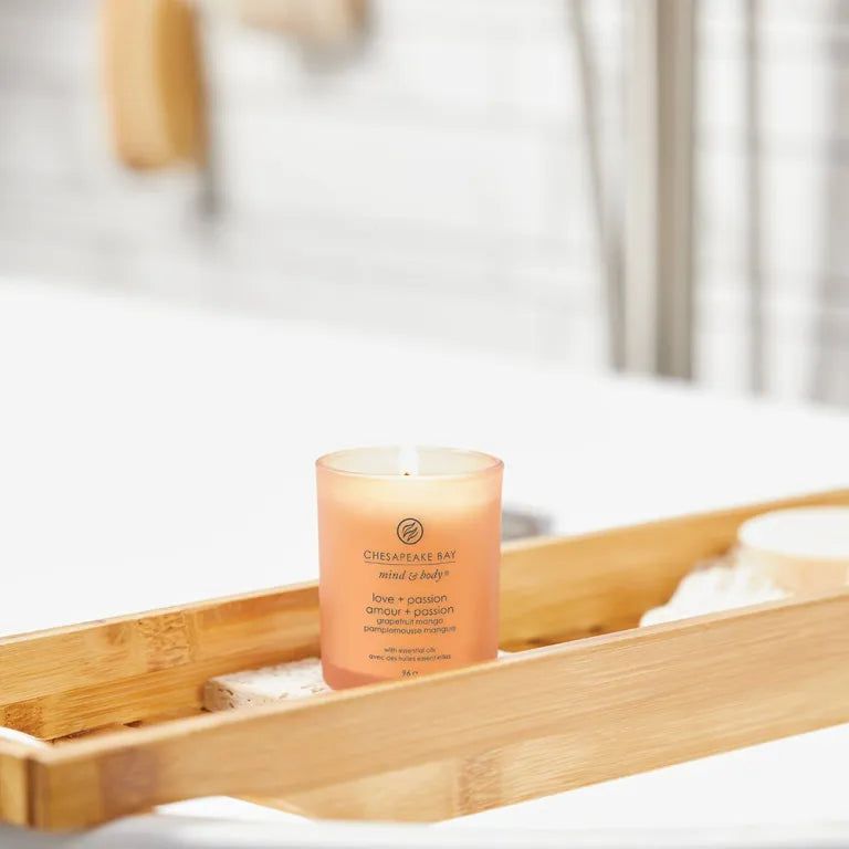 Bougie allumée sur une tablette de bain. Texte Chesapeake Bay mind & body, love + passion.