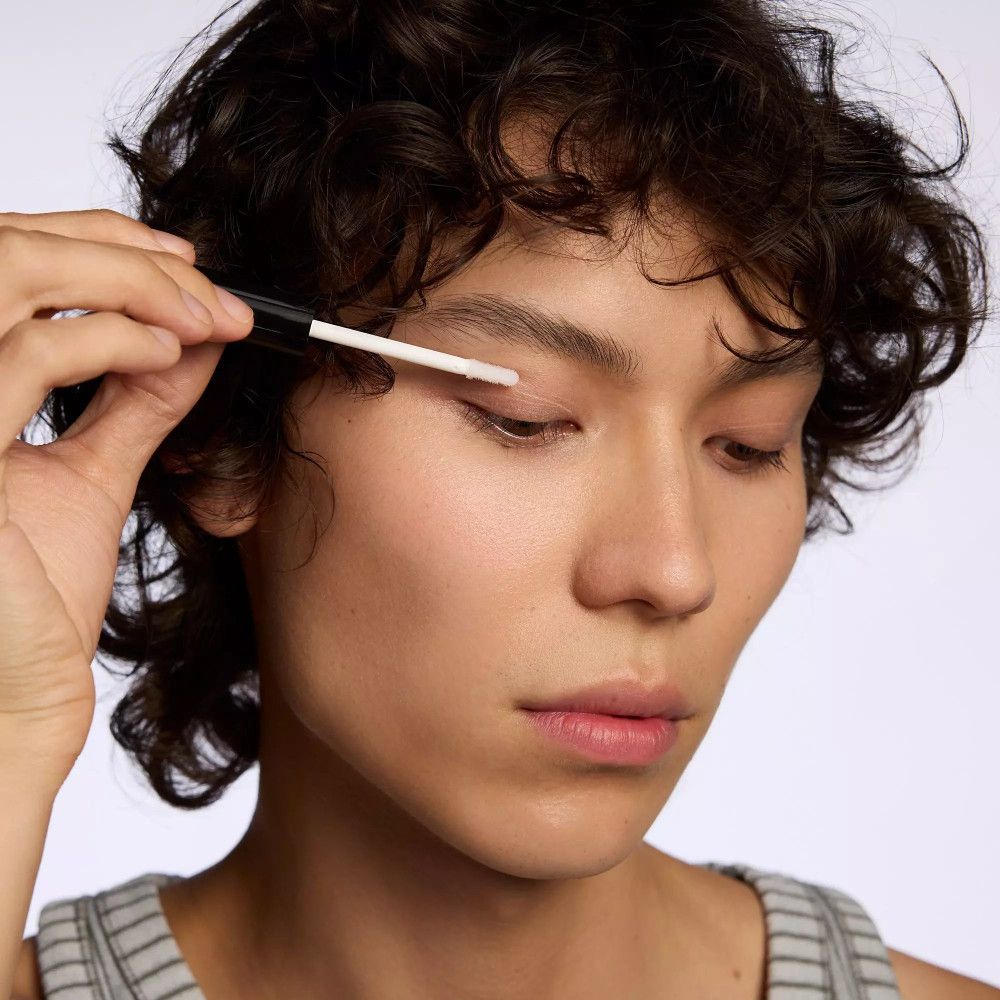 Persoon houdt applicator op ooglid. Huidtint, lichte huid. Toepassing van het product.