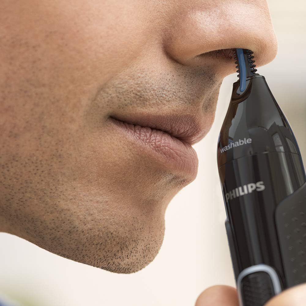 Man gebruikt Philips neus- en oortrimmer. Zwart apparaat bij neusgat, blauw trimdeel zichtbaar.