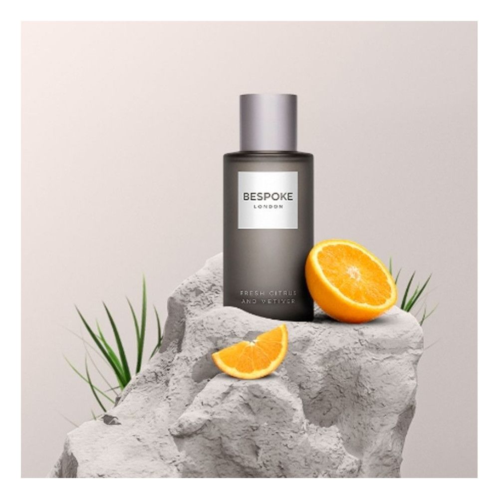 Flacon de parfum sur pierre avec oranges. Texte: Bespoke London, Fresh Citrus and Vetiver.