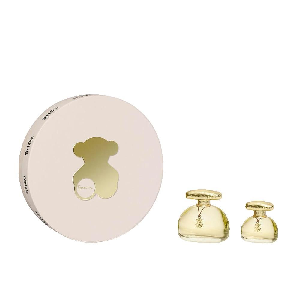 Ronde, crèmekleurige verpakking met berenuitsparing. Twee goudkleurige parfumflesjes met hangers. Opschrift TOUS.