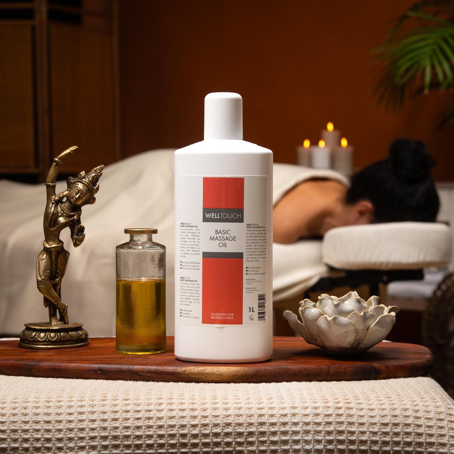 Witte fles met rood etiket "Welltouch Basic Massage Oil". Daarnaast een kleine glazen fles met gele vloeistof.