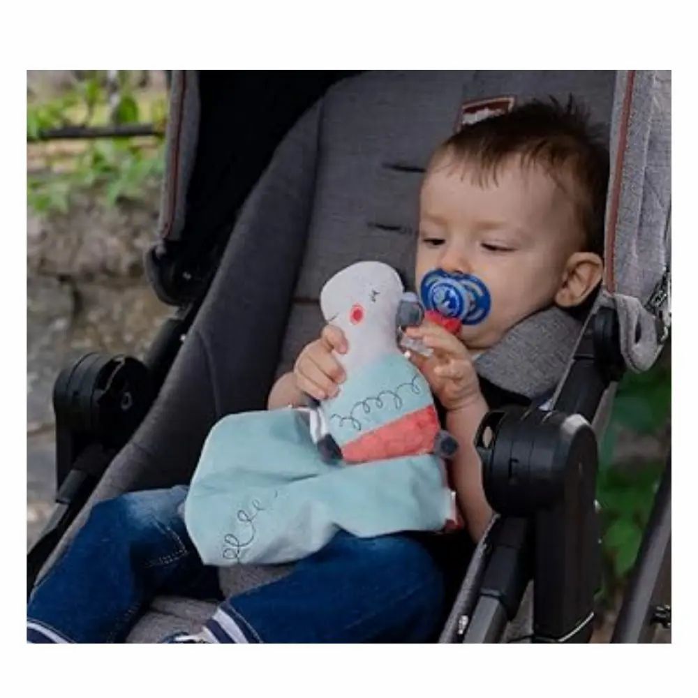 Enfant dans une poussette avec doudou et tétine. Tissu bleu, tête d'hippopotame.