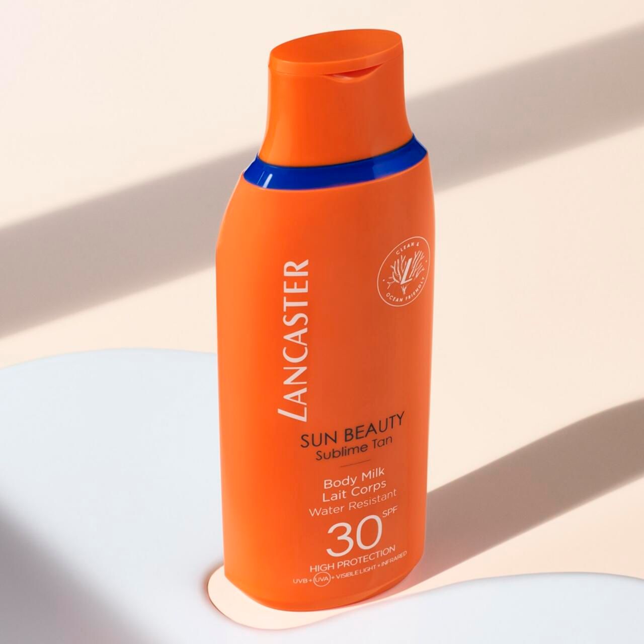 Bouteille orange avec accent bleu. Nom du produit et SPF 30 visibles. Texte: Lancaster, Sun Beauty, Body Milk, Water Resistant.