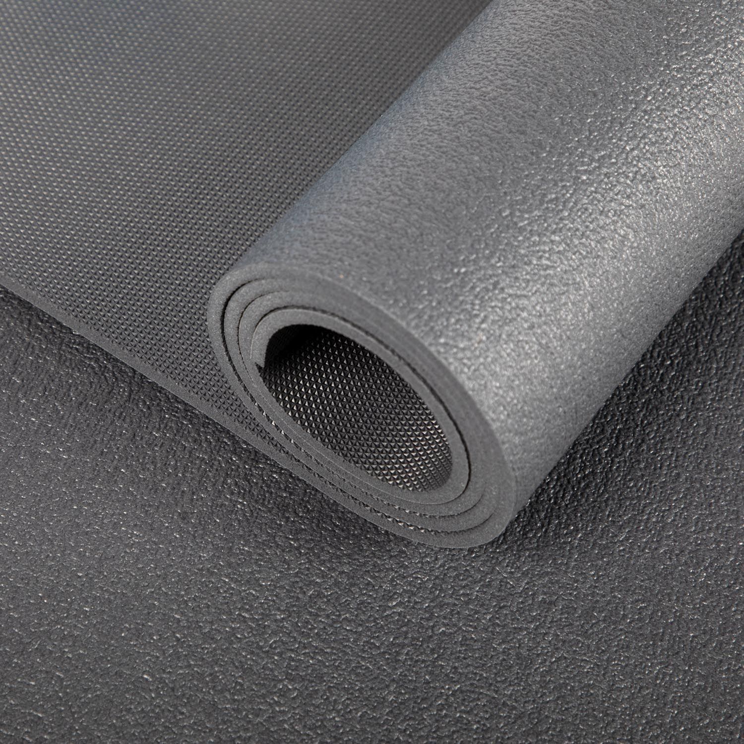 Detail van een opgerolde, donkergrijze yogamat. Op witte achtergrond.