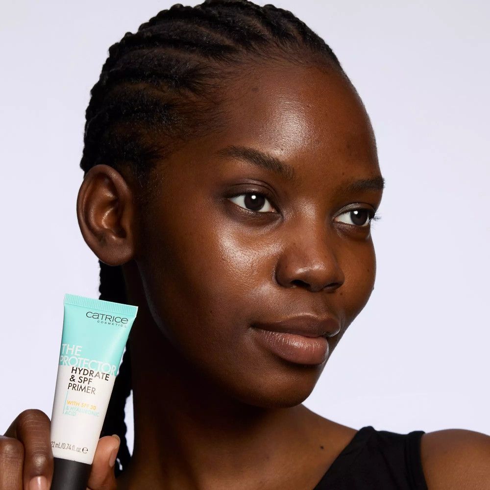 Femme tenant un tube. Inscription: Catrice, THE PROTECTOR HYDRATE & SPF PRIMER. 22 ml.