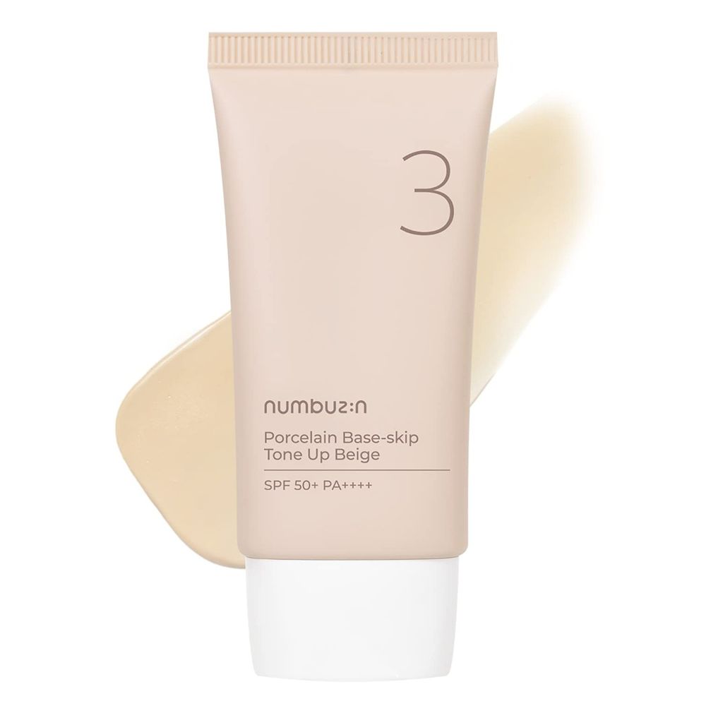 Tube beige avec bouchon blanc et trace de crème. Inscription : n:umbuz:in, Porcelain Base-skip, Tone Up Beige, SPF 50+ PA++++. Chiffre 3.