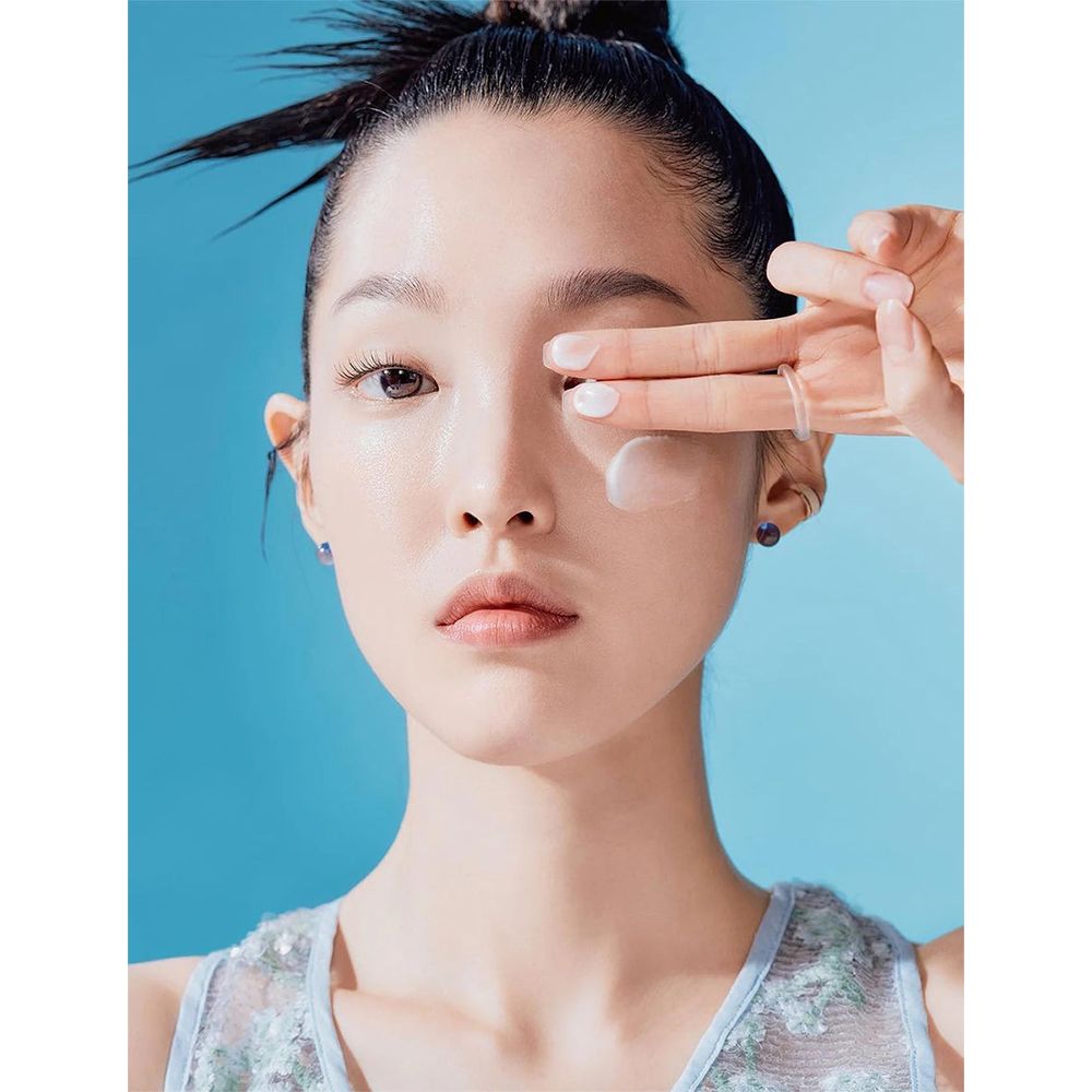 Femme appliquant de la crème solaire sur son visage. Produit non identifiable.