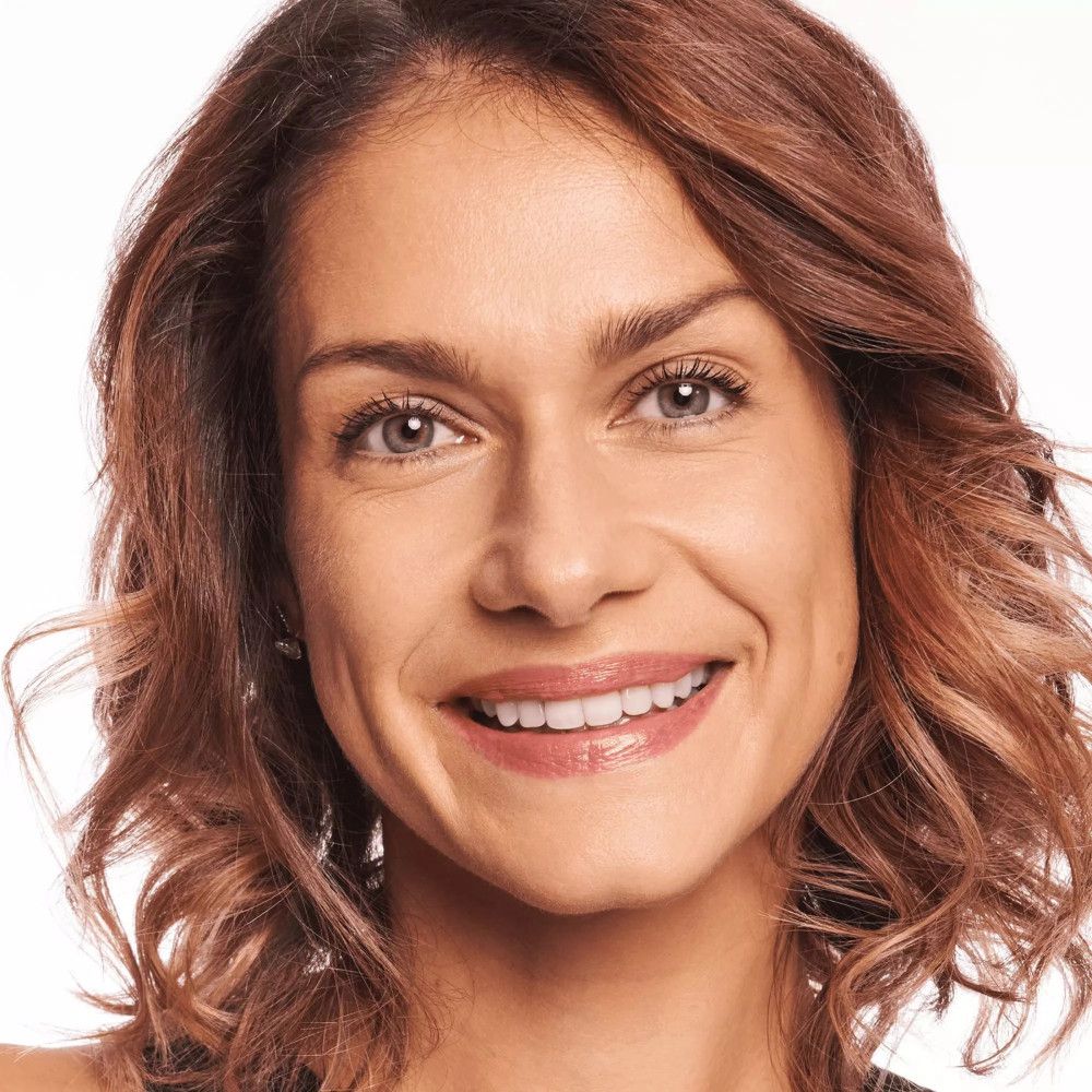 Portrait d'une femme aux cheveux bruns. Elle sourit.