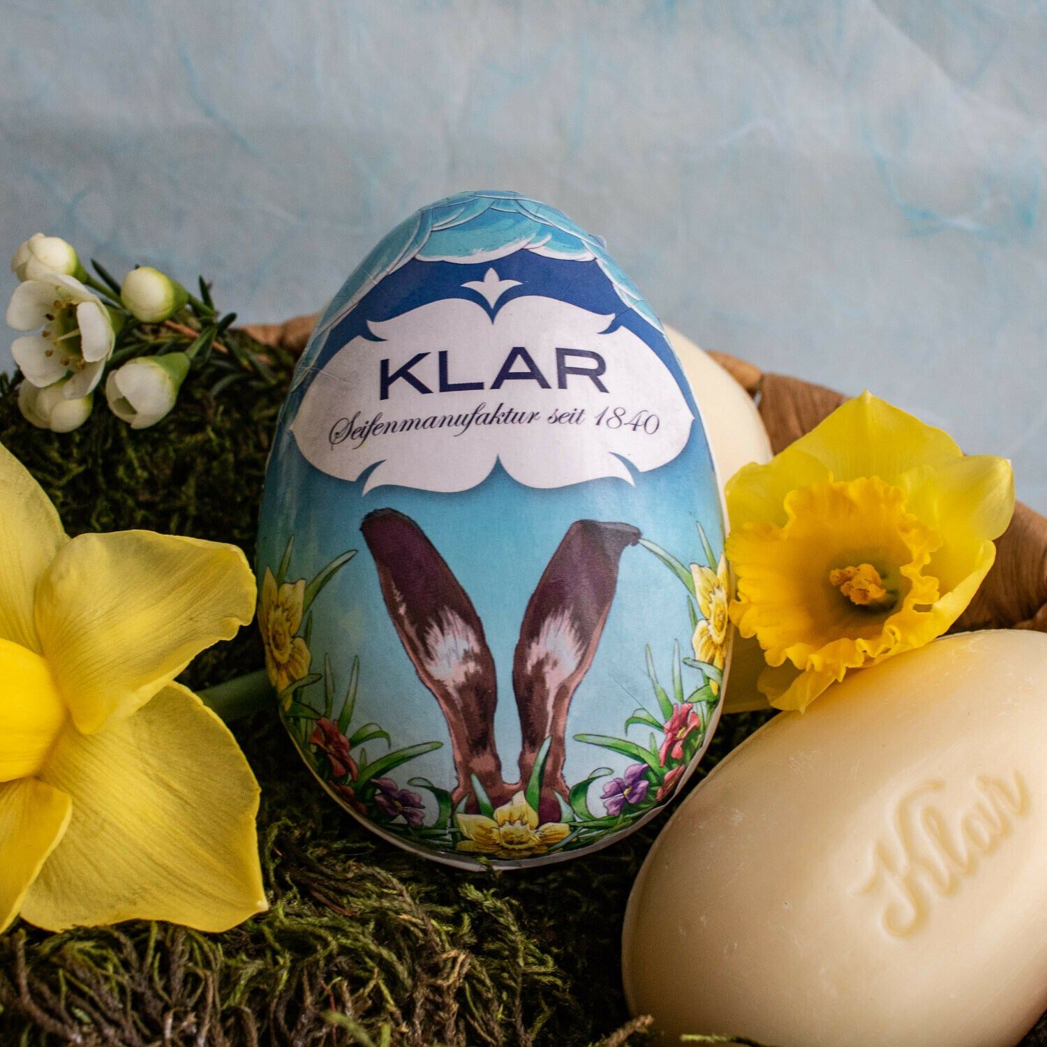 Emballage œuf de Pâques avec oreilles de lapin, savon et fleurs. Savon avec inscription Klar. Sur mousse et panier.