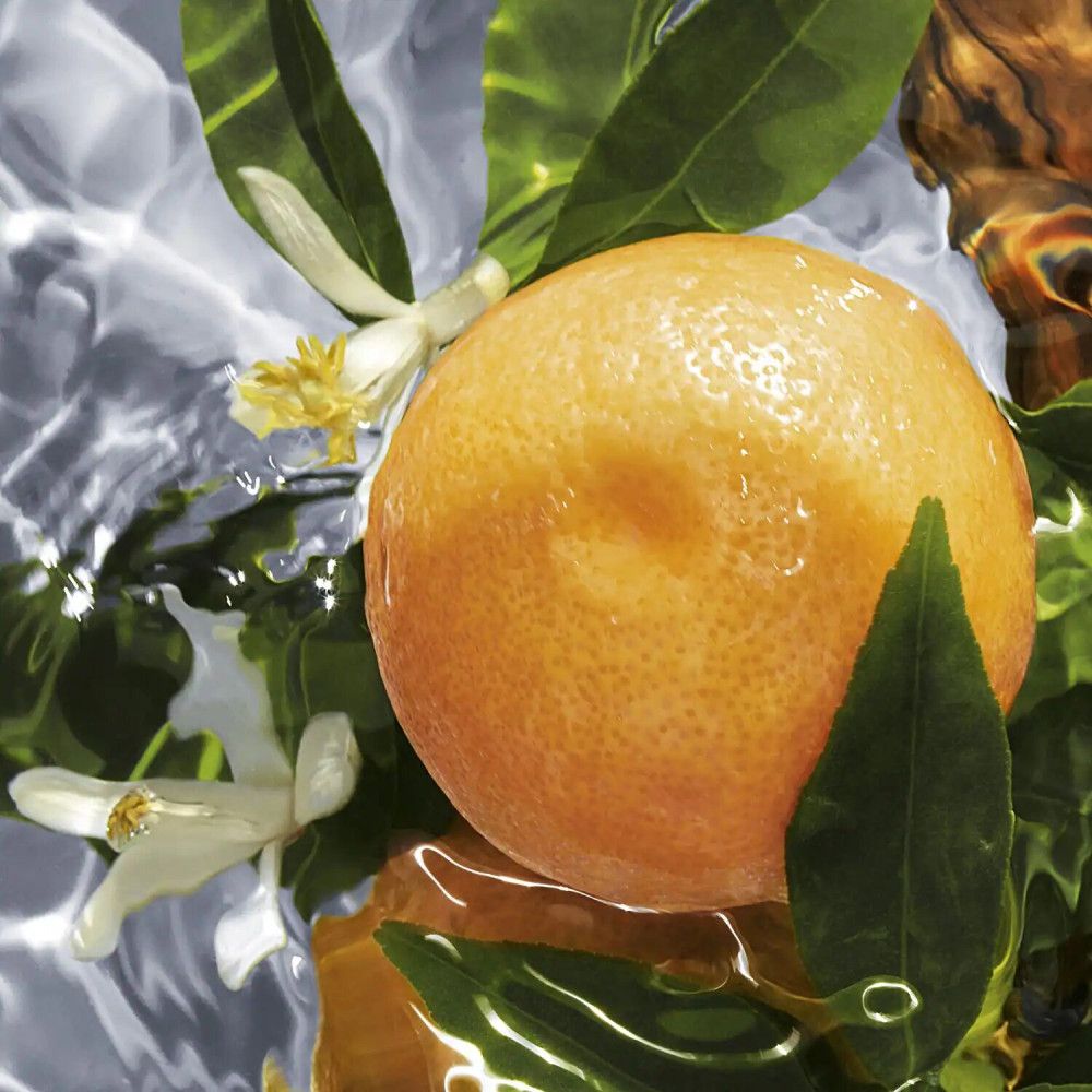 Orange dans l'eau, entourée de feuilles et de fleurs. Gros plan.