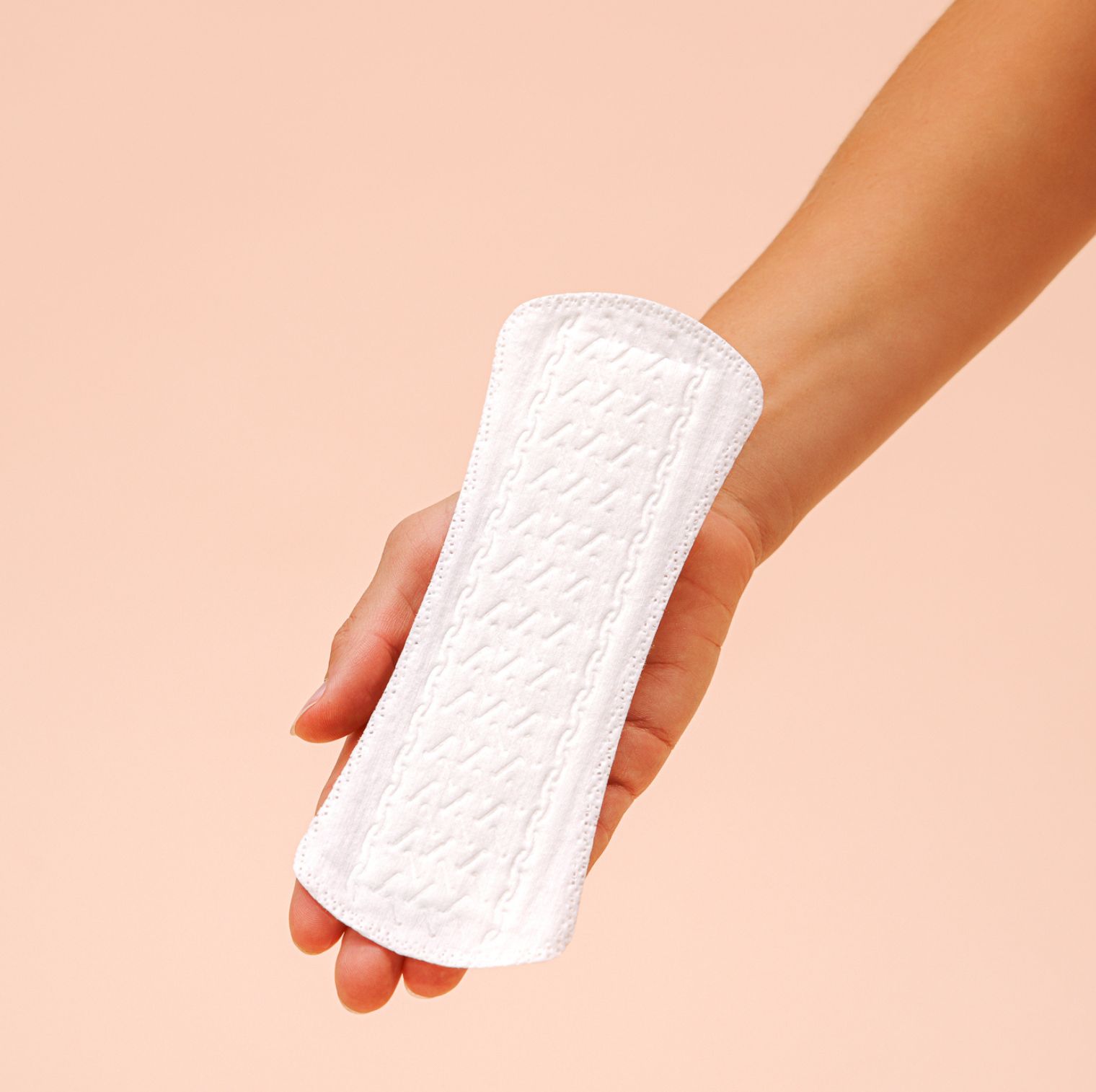 Witte inlegkruisje met reliëf, in hand. Roze achtergrond.