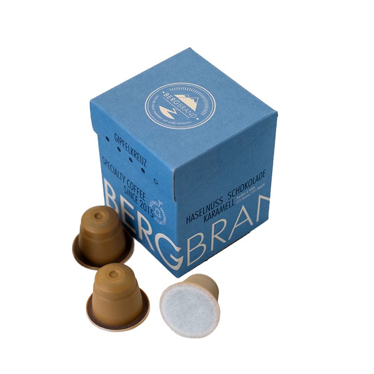 Boîte bleue avec logo BERGBRAND et capsules. Capsules marron à côté.