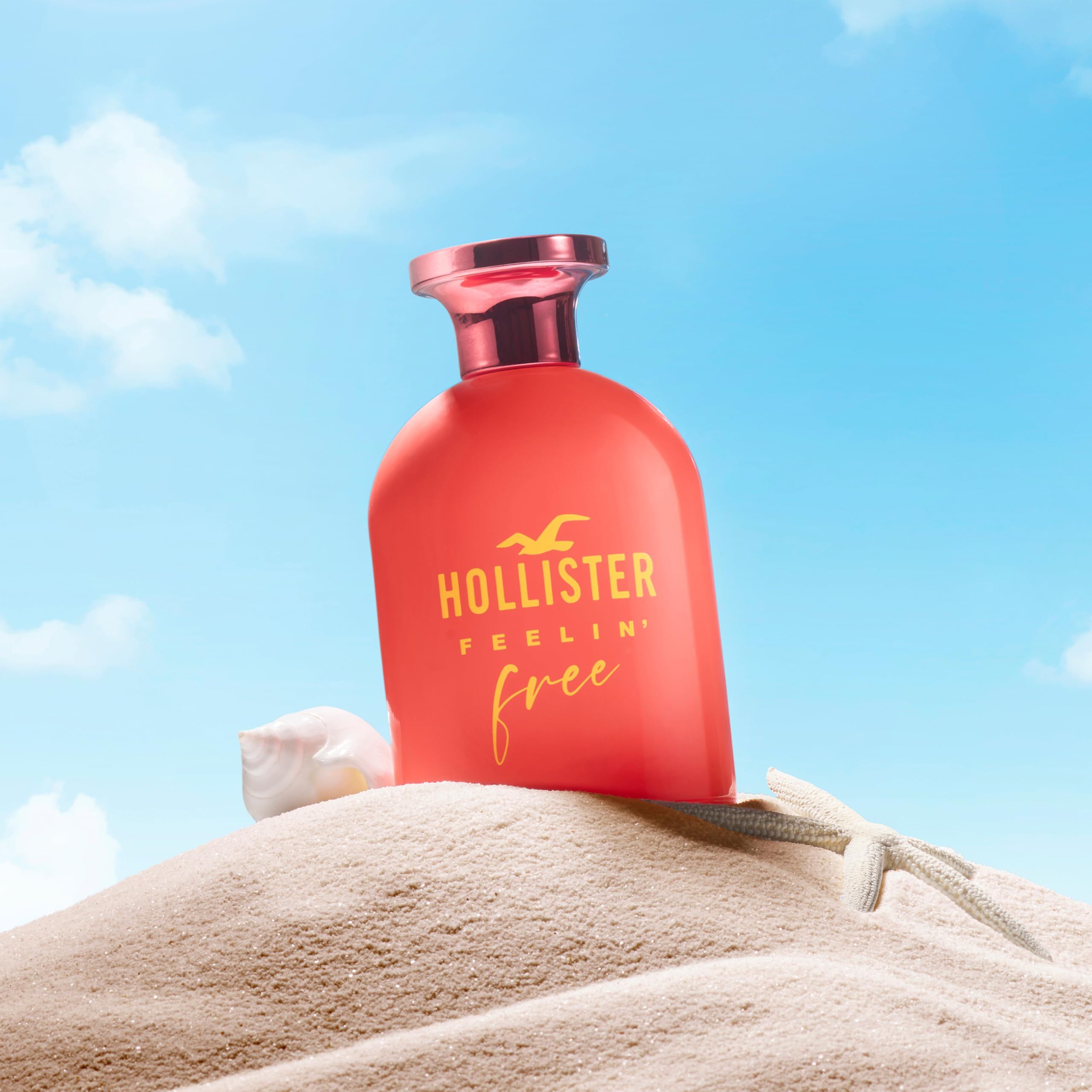 Rode fles met gele tekst. Opschrift: Hollister Feelin' Free. Roze dop. Achtergrond: zand.