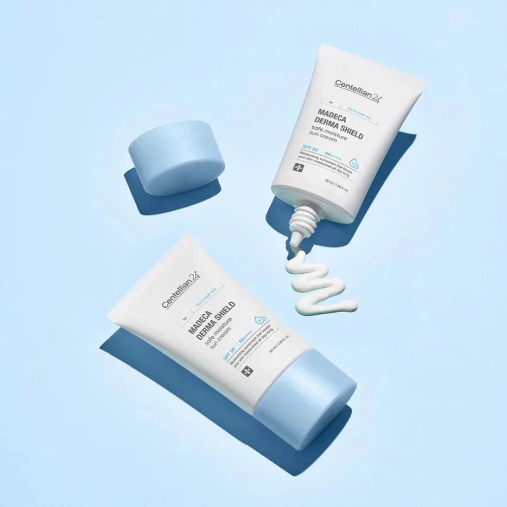 Trois tubes de crème solaire, un avec le bouchon ouvert, un avec de la crème qui sort. Emballage bleu et blanc avec nom du produit et logo.