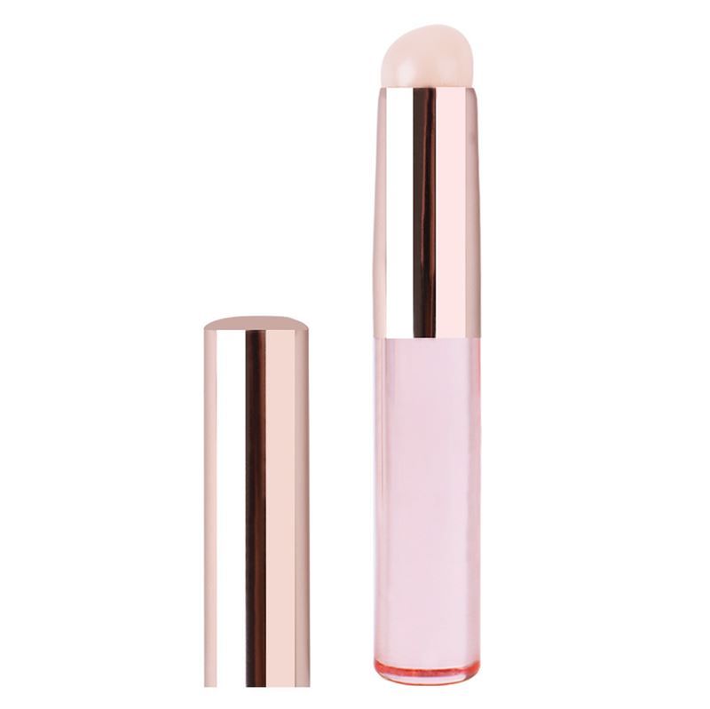 Pinceau avec manche rose et applicateur clair. À côté, un capuchon.