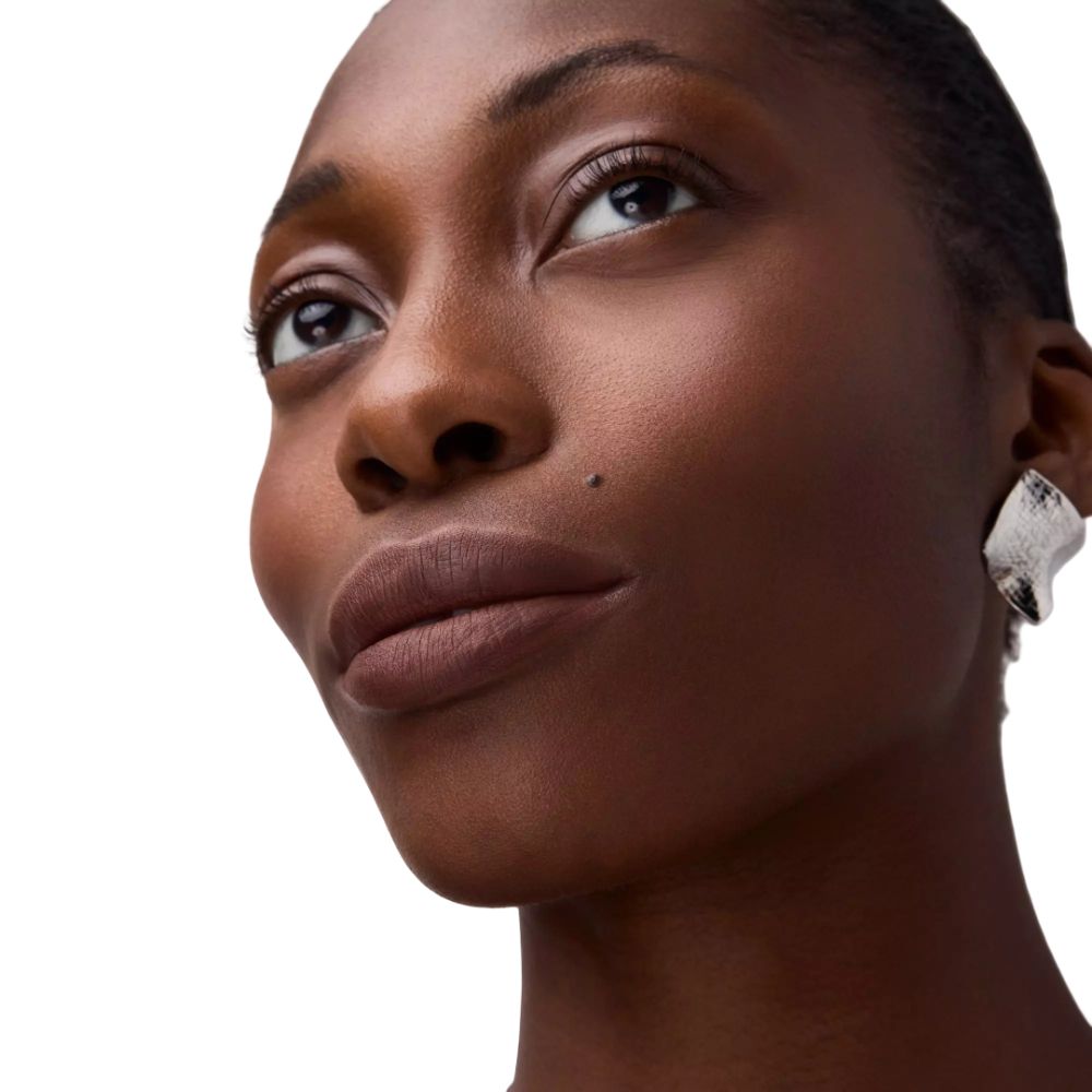 Portrait d'une femme avec du rouge à lèvres. Couleur des lèvres marron. Peau foncée, regard vers le haut.