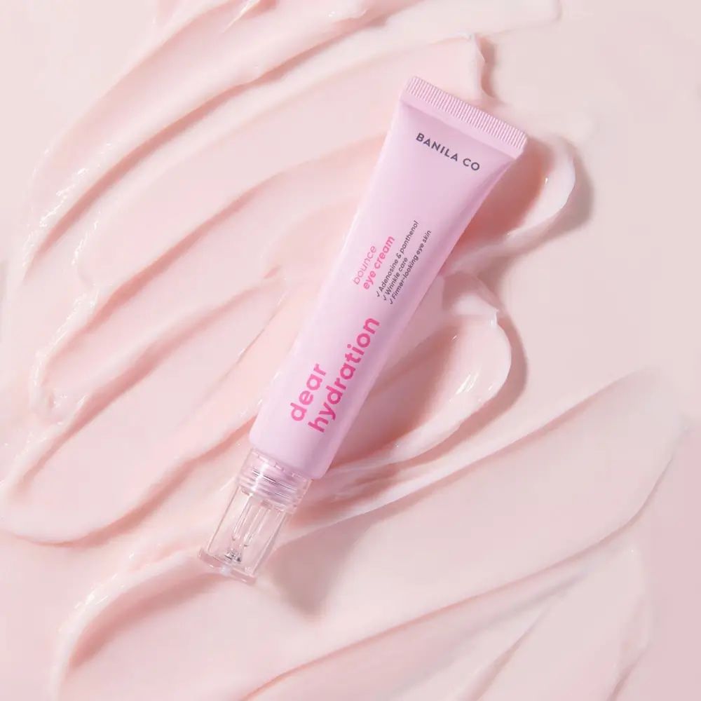 Tube de crème pour les yeux rose sur fond rose. Le tube porte l'inscription "BANILA CO Dear Hydration".