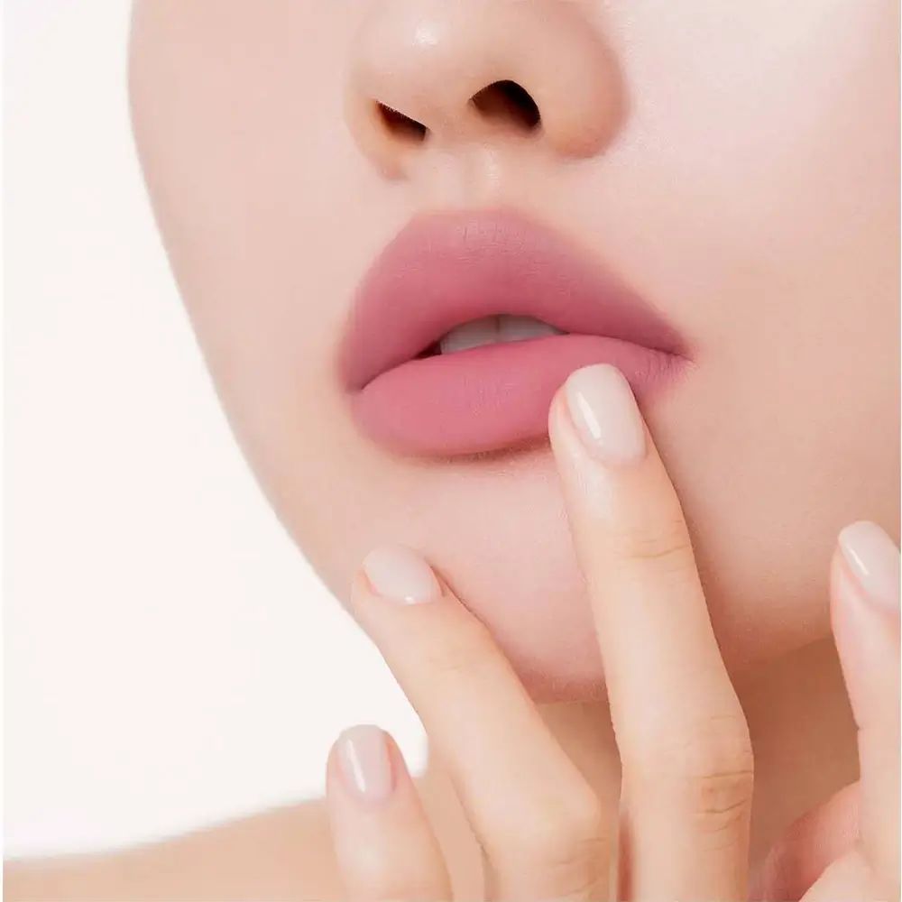 Close-up van lippen met roze lippenstift. Vinger raakt de lippen aan. Lichte huidskleur.