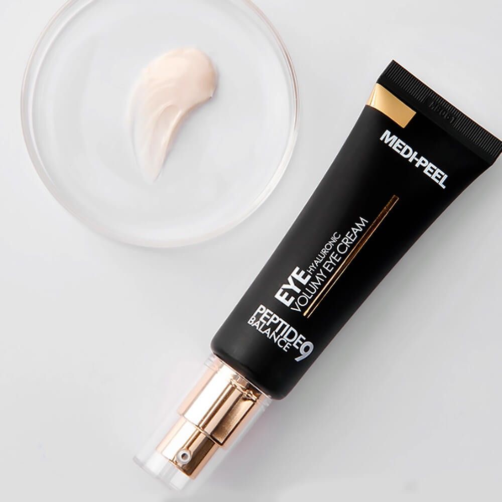 Tube noir avec bouchon doré et un échantillon de crème à côté. Inscription : MEDI-PEEL PEPTIDE 9 HYALURONIC VOLUMY EYE CREAM.
